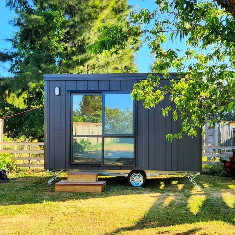 The Cabin Company cabin in situ in a rural setting between a white fence and tree