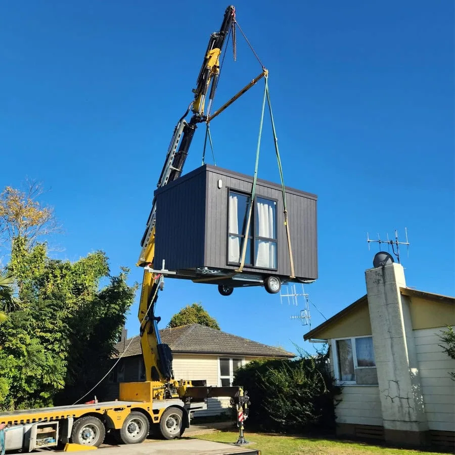 The Cabin Company cabin being hoisted by a crane into position in a front yard